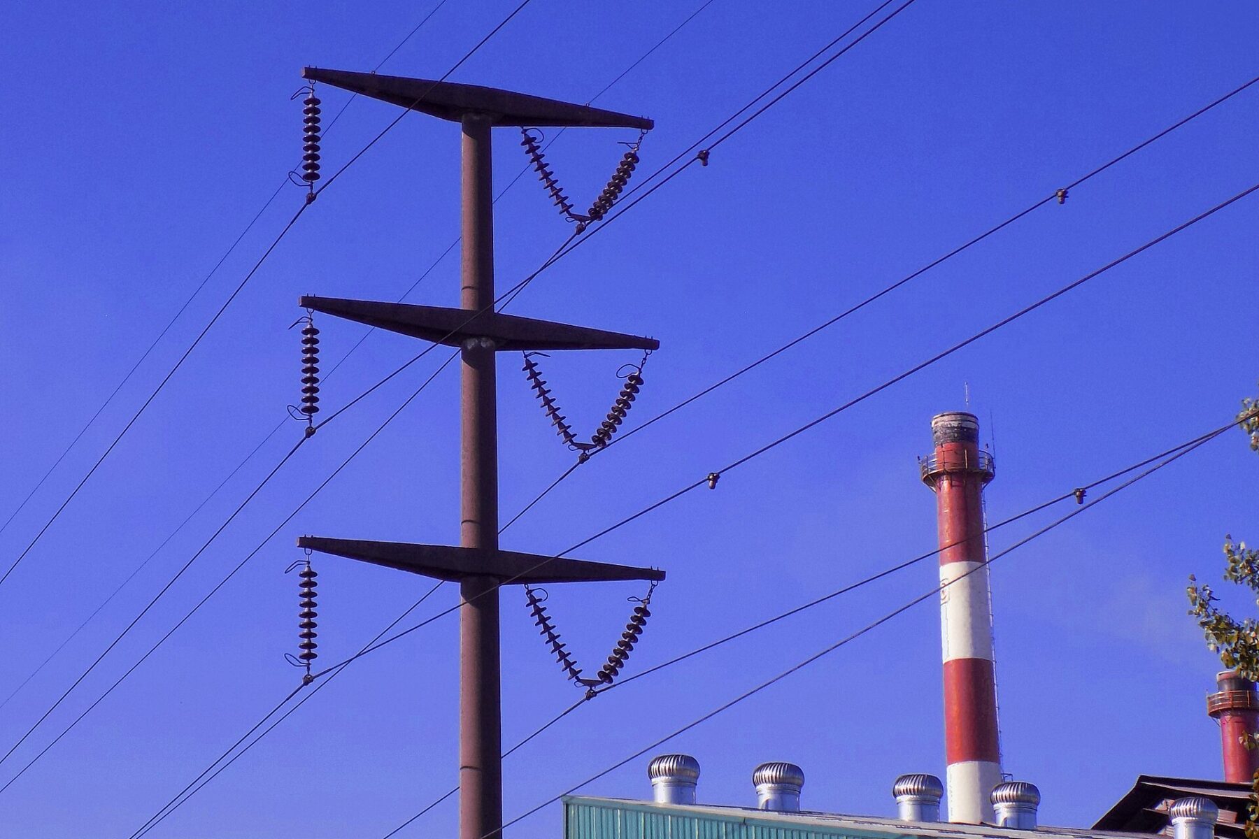 A high-voltage transmission tower beside an industrial plant in Buenos Aires province