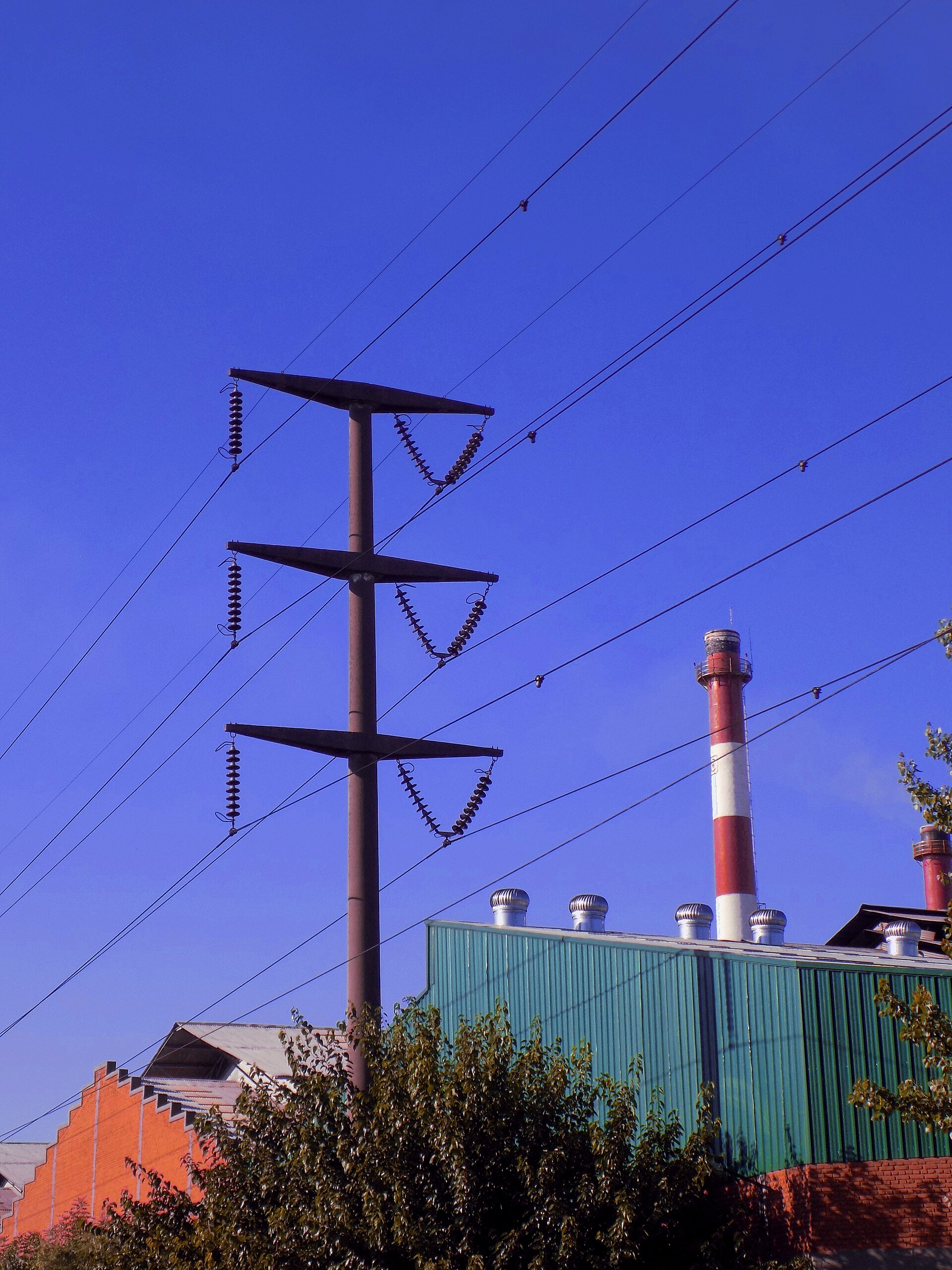 A high-voltage transmission tower beside an industrial plant in Buenos Aires province