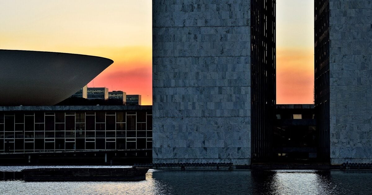 The twin towers and dome of Brazil’s National Congress in Brasília silhouetted against an orange dusk sky