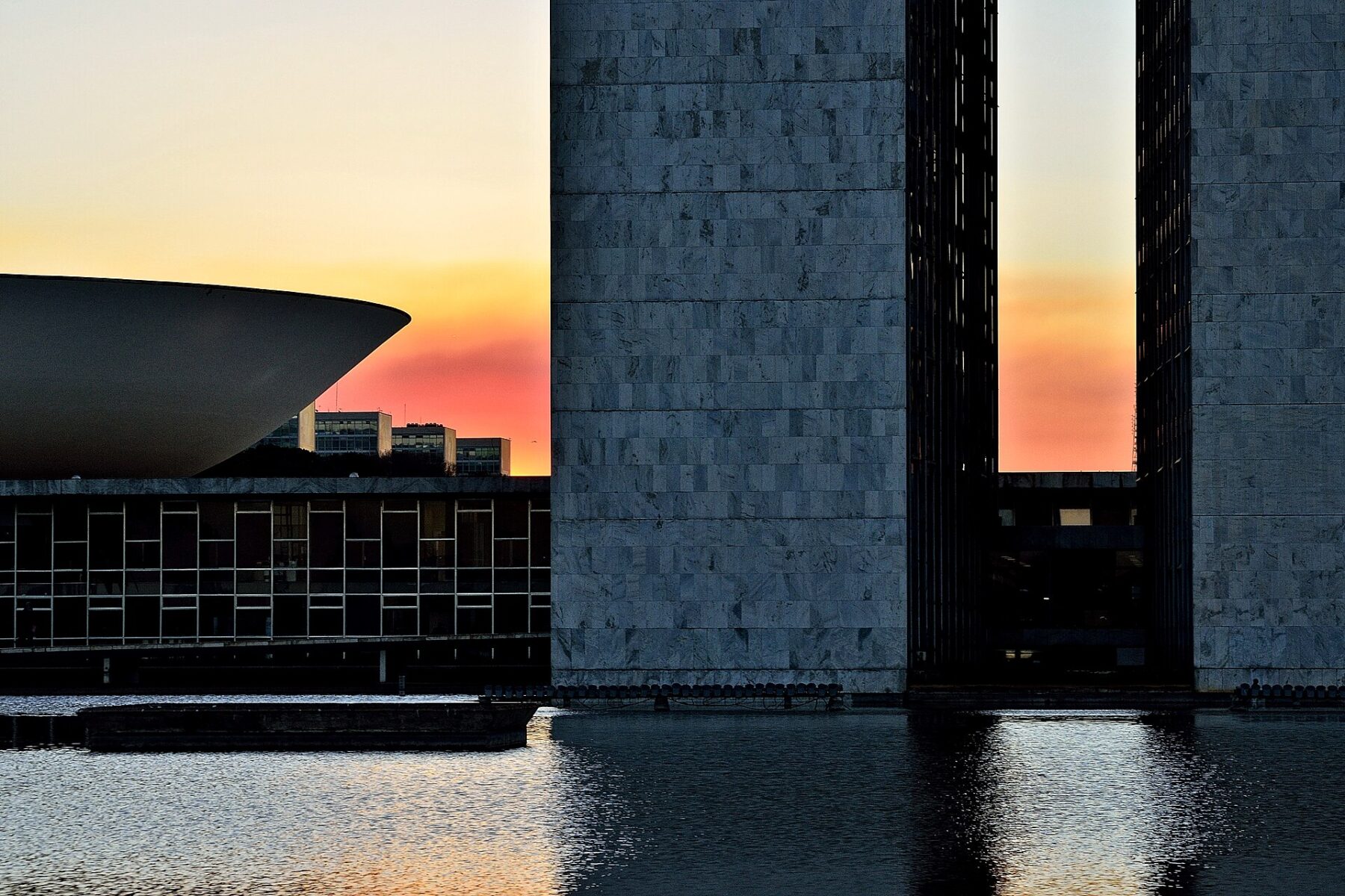 The twin towers and dome of Brazil’s National Congress in Brasília silhouetted against an orange dusk sky