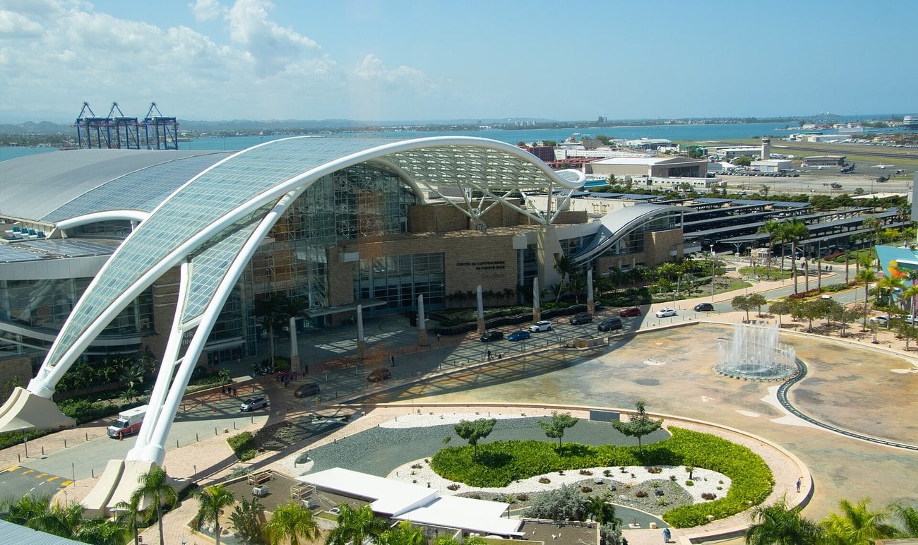 The glass and steel Puerto Rico Convention Center in San Juan, with the harbour and airport behind it.