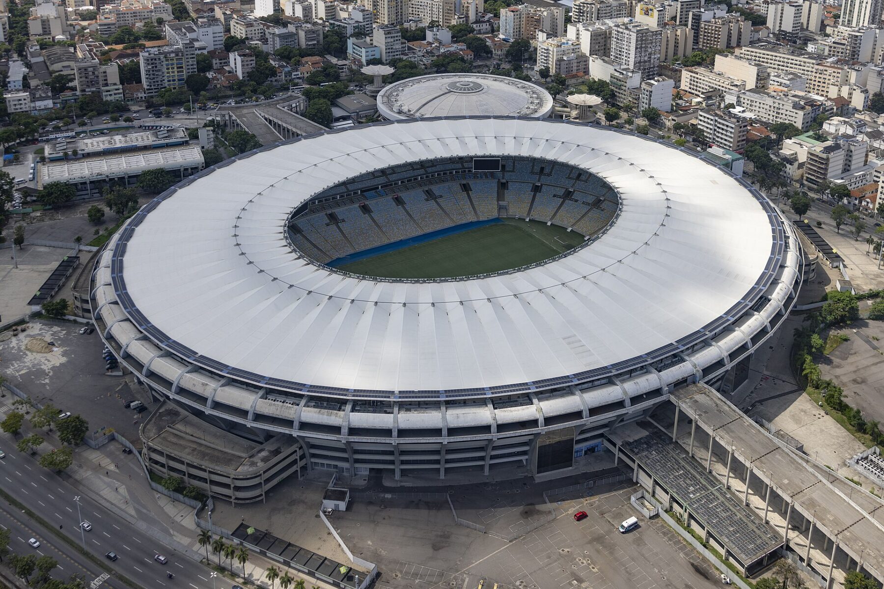 Aerial view of the Maracanã stadium in Rio de Janeiro, its white roof ring surrounding the pitch, with the city around it.
