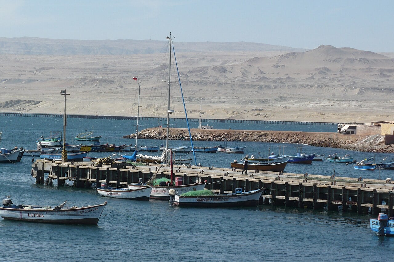 Marcona port area: fishing boats moored at a wooden pier in San Juan de Marcona, Peru, with desert hills behind