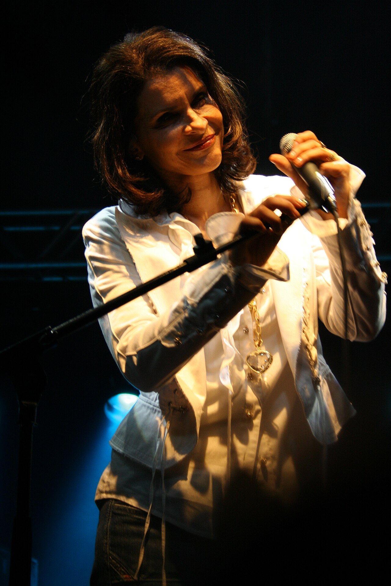 Brazilian singer Marina Lima performing live on stage with a microphone.