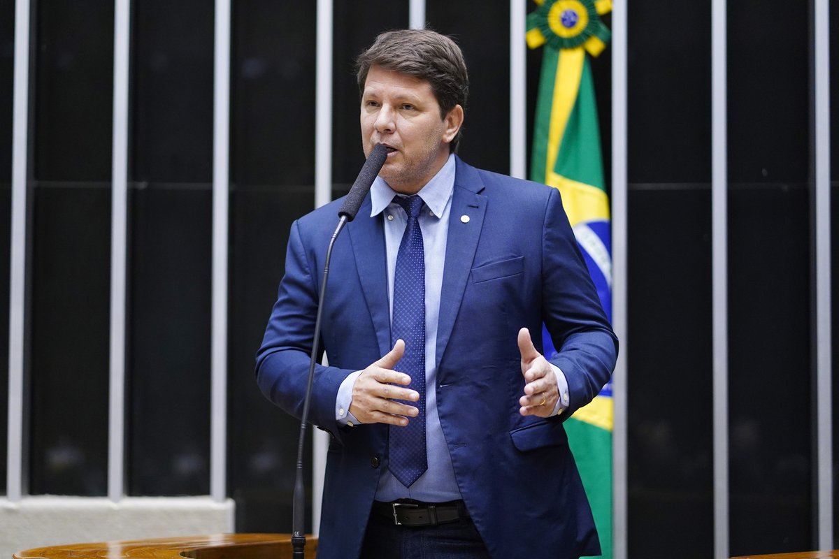 Federal deputy Mario Frias speaking at the podium of the Chamber of Deputies in Brasilia, with a Brazilian flag behind him