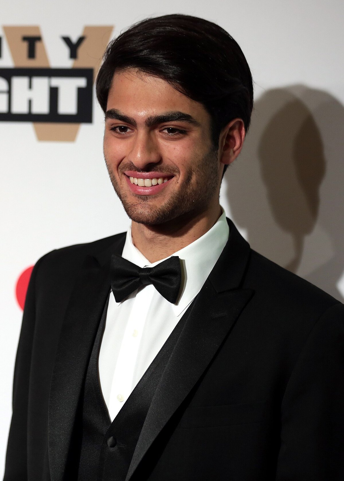 Matteo Bocelli in a black tuxedo and bow tie, smiling at a press event