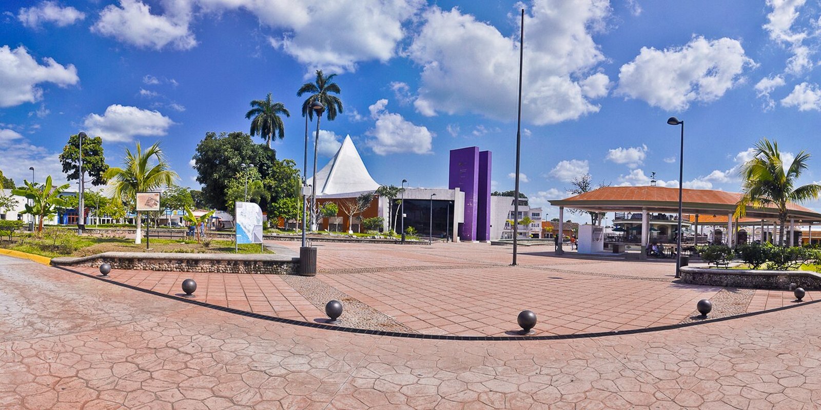 Migrant caravan departure point: Parque Bicentenario in Tapachula, Chiapas, Mexico, a paved square with palm trees and a white tent roof