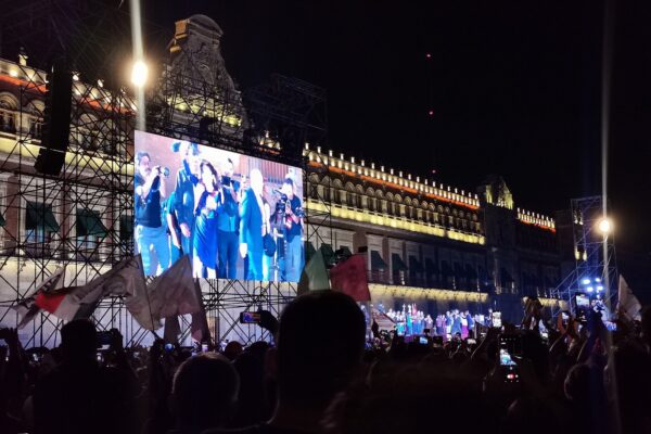 Sheinbaum Zócalo speech: crowd in Mexico City's Zócalo before the lit National Palace, with Claudia Sheinbaum on a giant screen