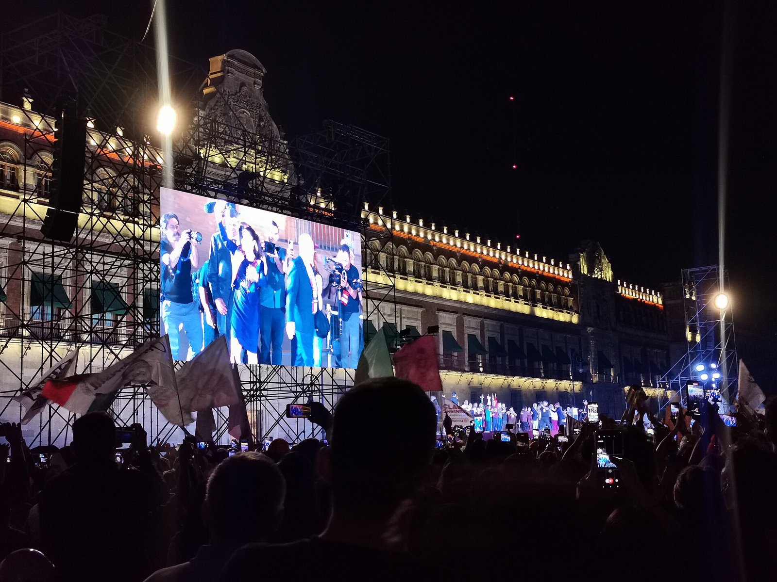 Sheinbaum Zócalo speech: crowd in Mexico City’s Zócalo before the lit National Palace, with Claudia Sheinbaum on a giant screen