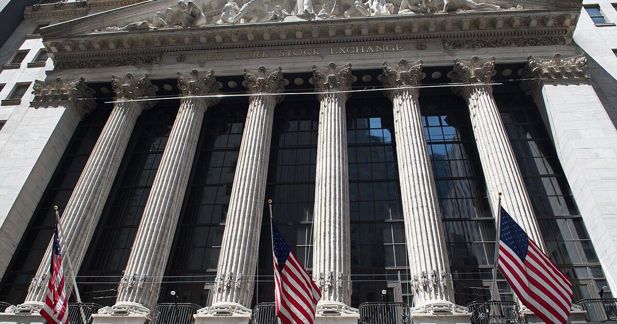 The columned facade of the New York Stock Exchange with three American flags hanging below the pediment