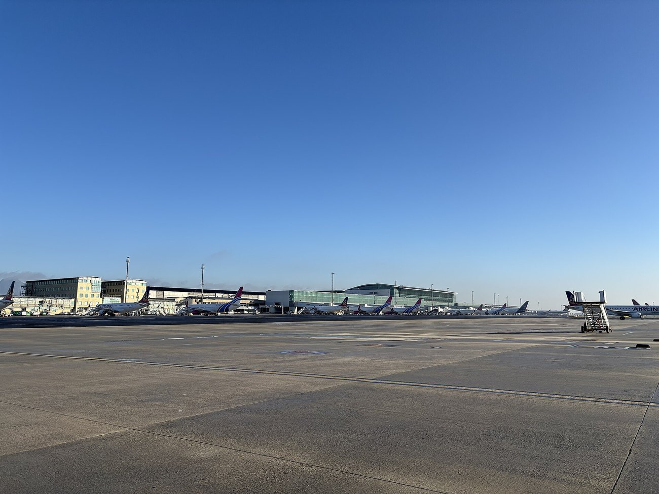 Regional aircraft parked on the apron at Cape Town International Airport under a clear sky.