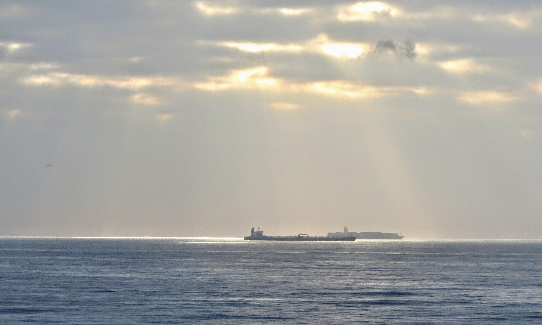 Oil tankers waiting offshore on a calm sea under breaking clouds, the diesel supply the G7 is trying to ease