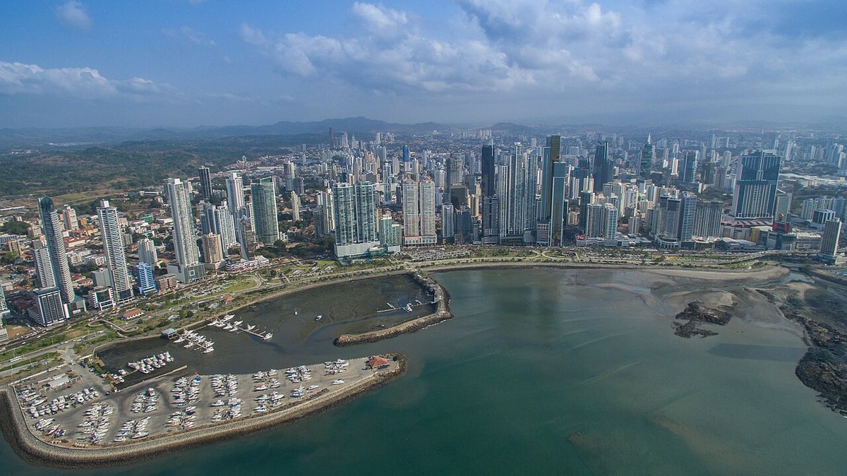 An aerial view of Panama City's financial district, with high-rise towers along the bay and a marina in the foreground