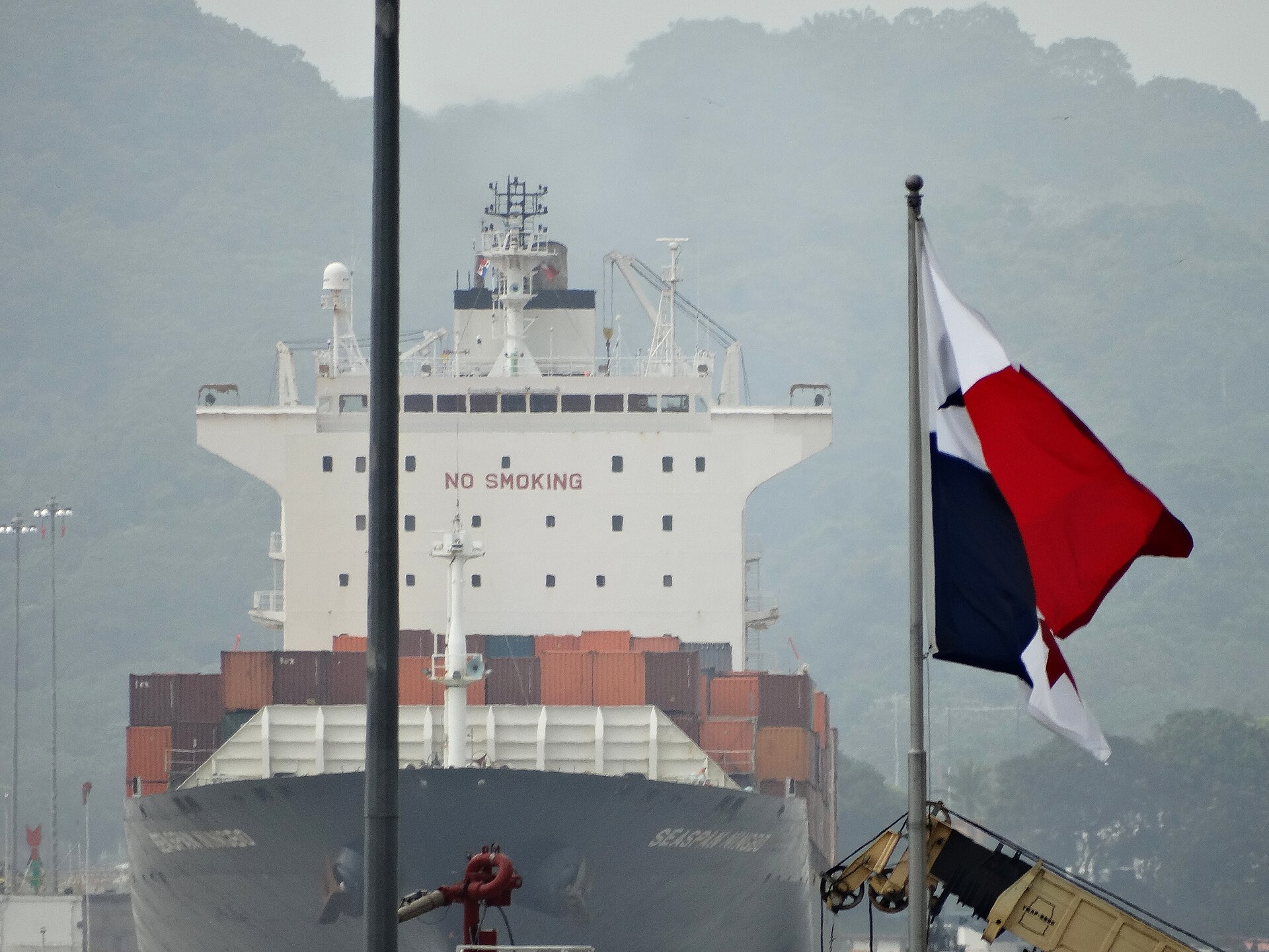 Panama explained 2026 — a container ship enters the Miraflores locks beside a Panamanian flag