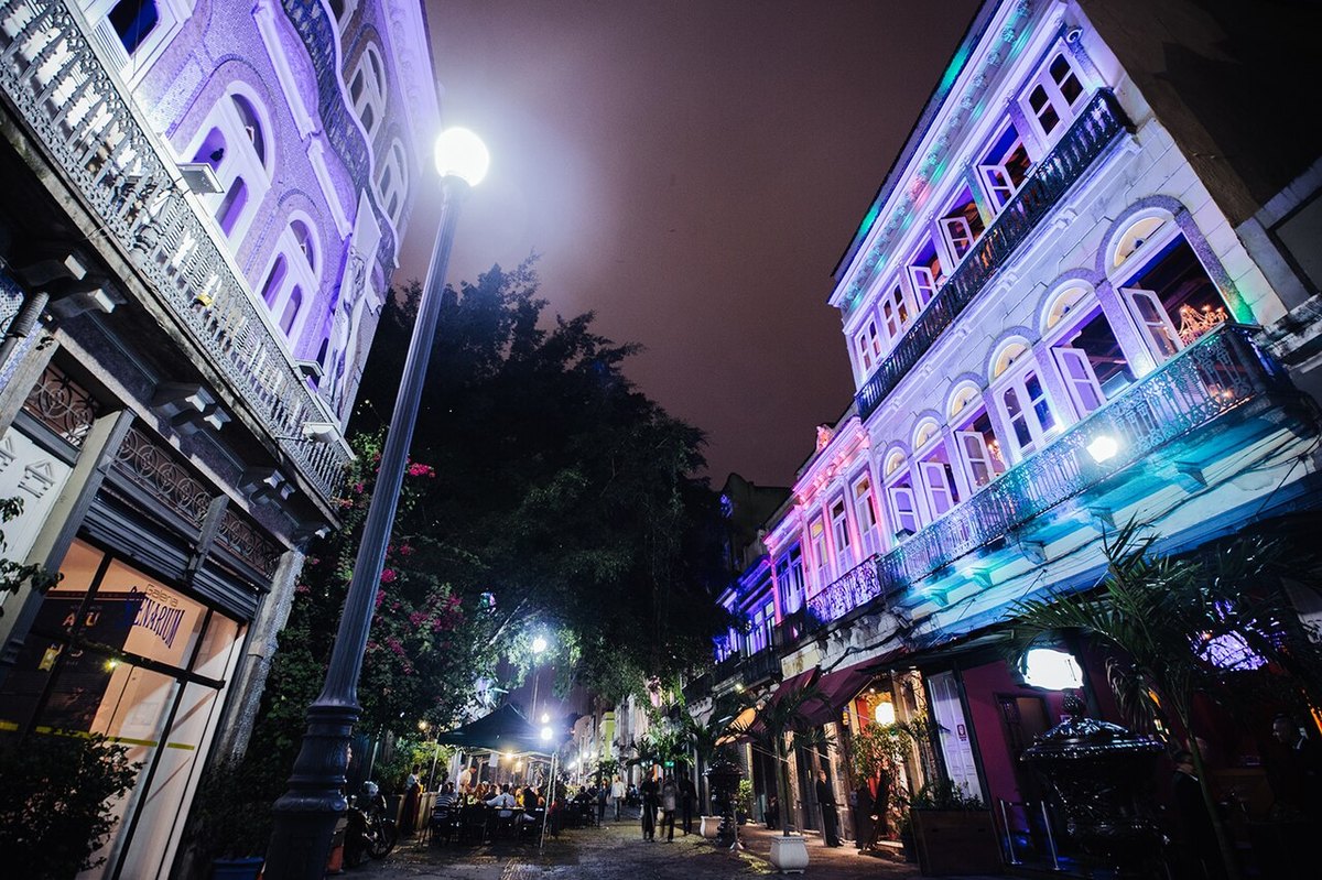 Lit nineteenth-century houses on Rua do Lavradio at night, with tables and people on the street outside Rio Scenarium