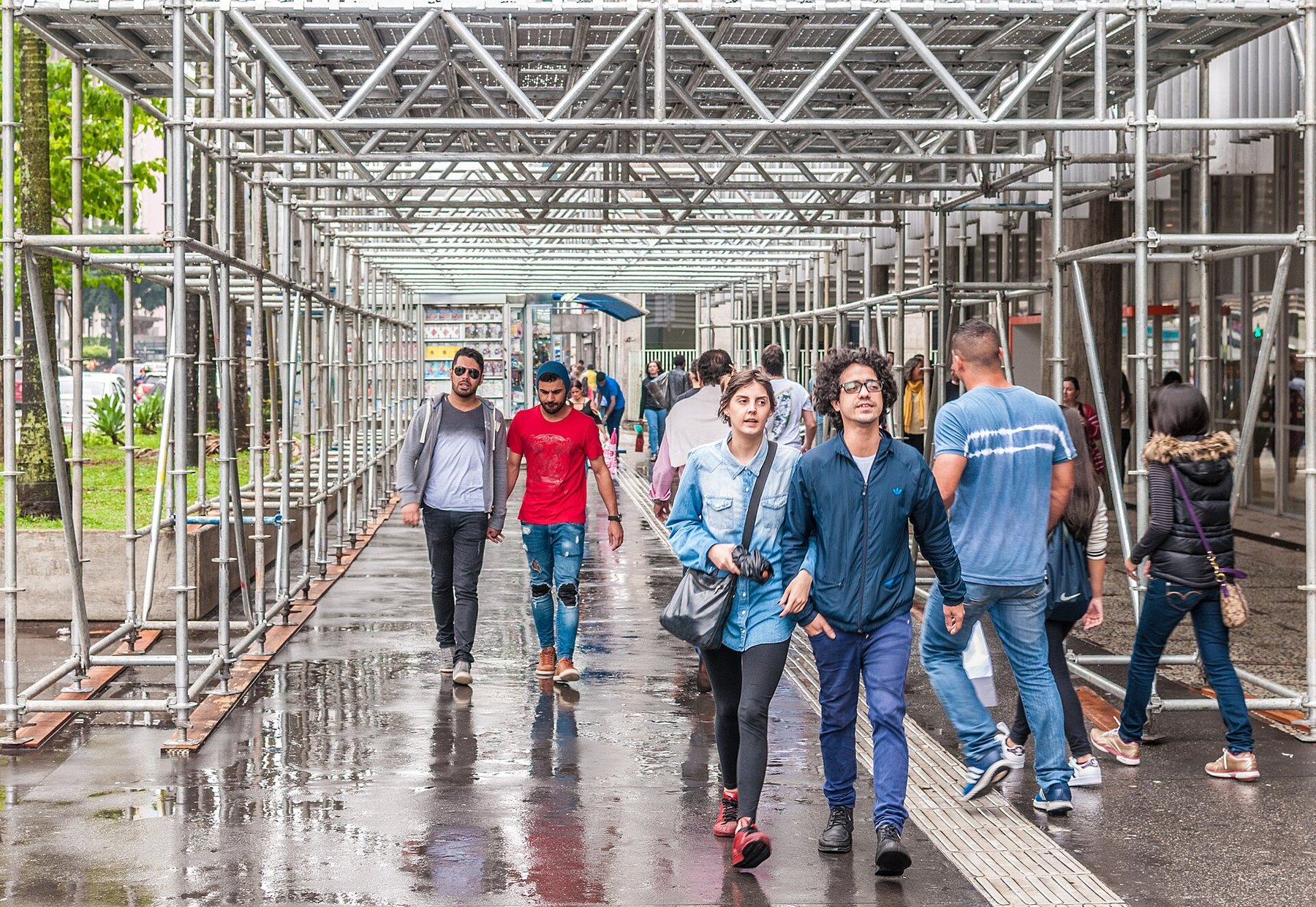 People walking through a covered construction walkway