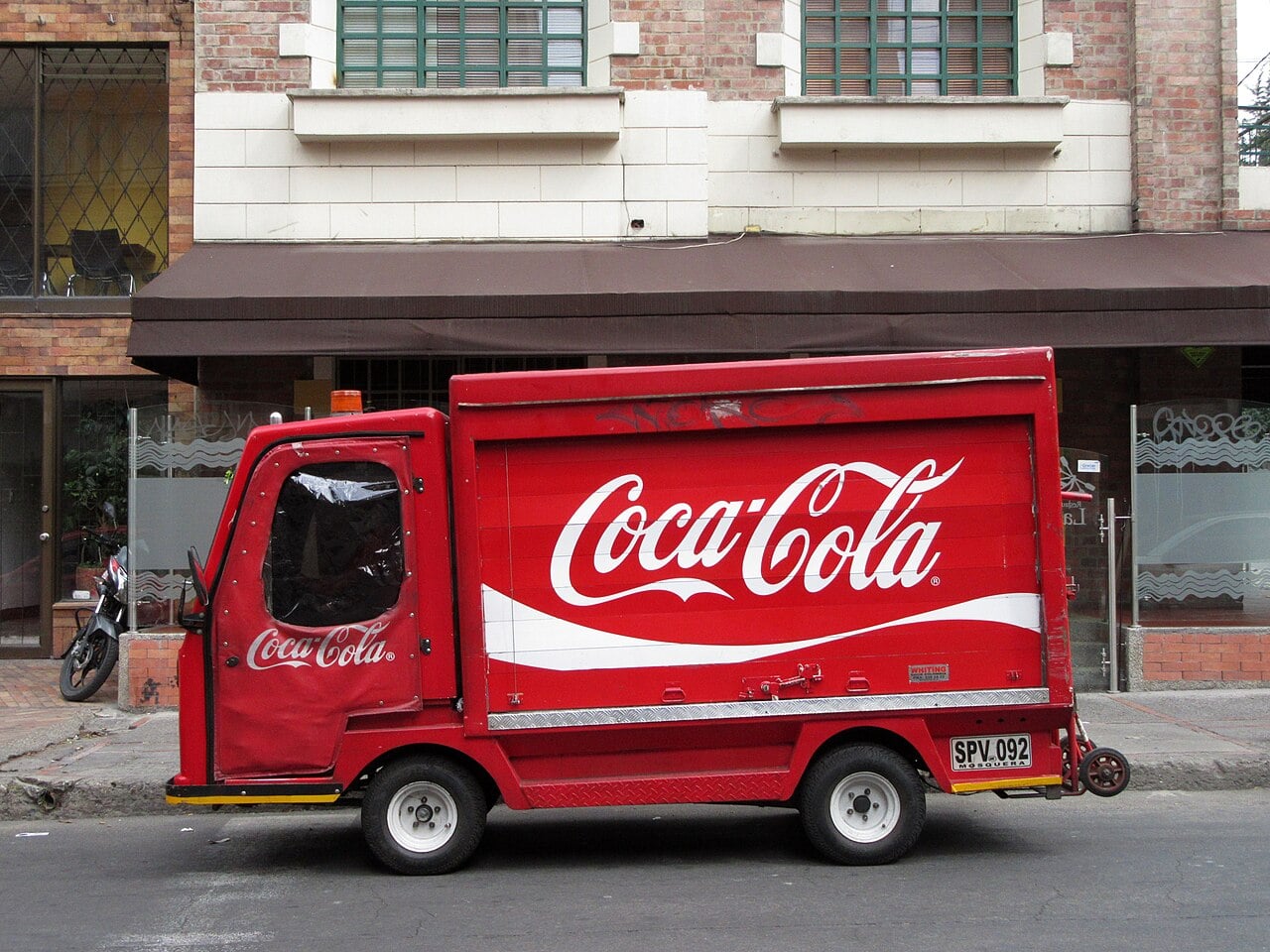 A red Coca-Cola delivery truck parked on a street in Bogota, Colombia