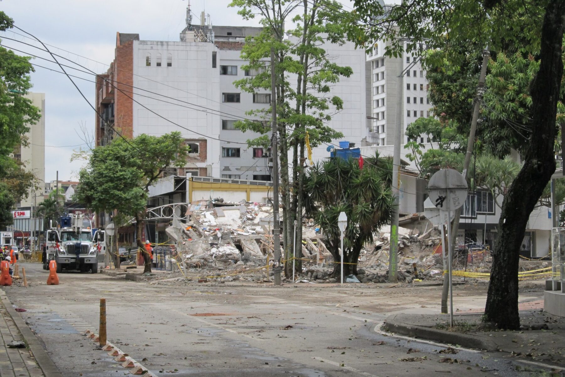 Collapsed building rubble on a street with recovery vehicles
