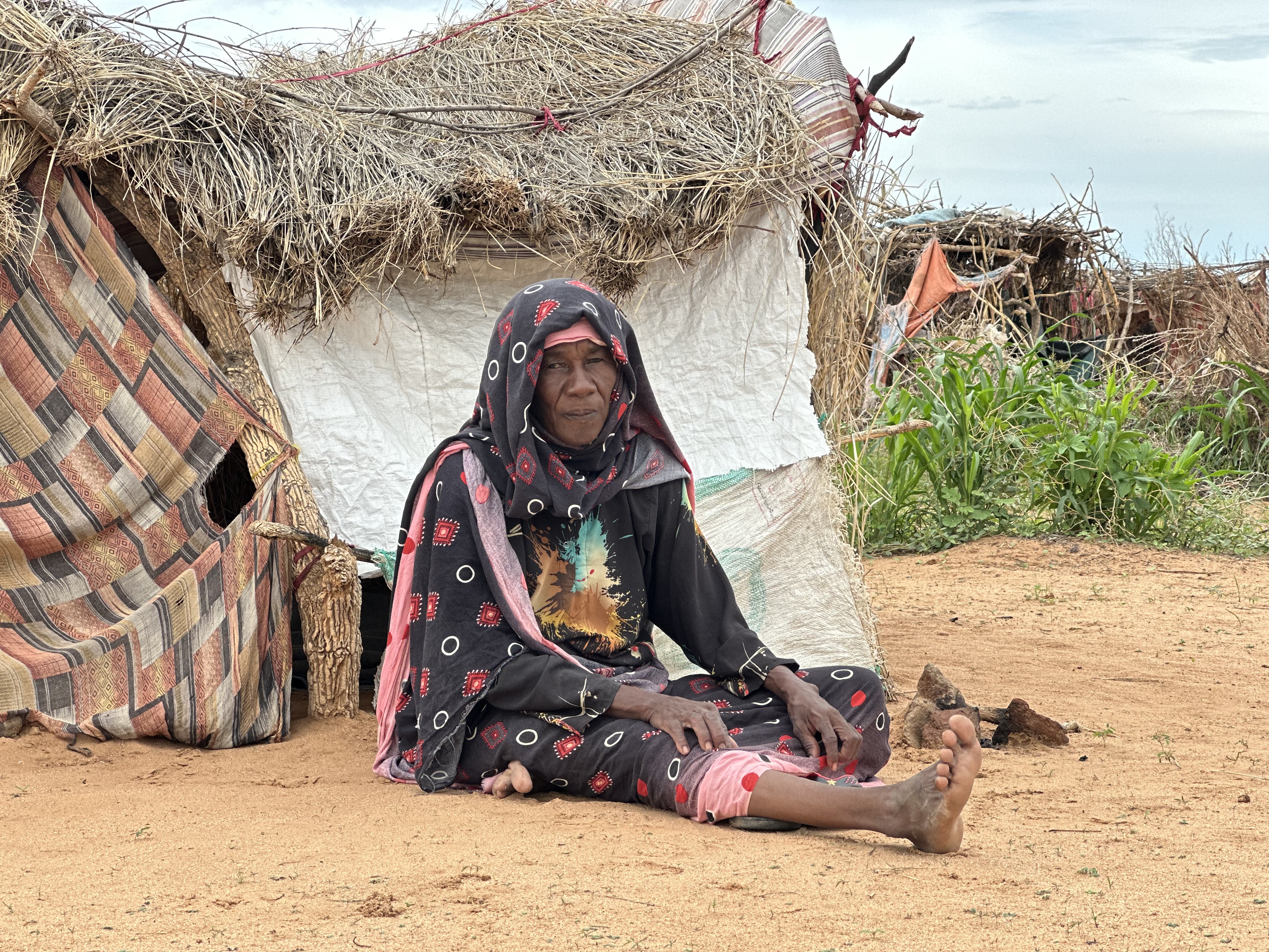 A displaced woman who fled El Fasher sits outside her makeshift shelter in Tawila, North Darfur