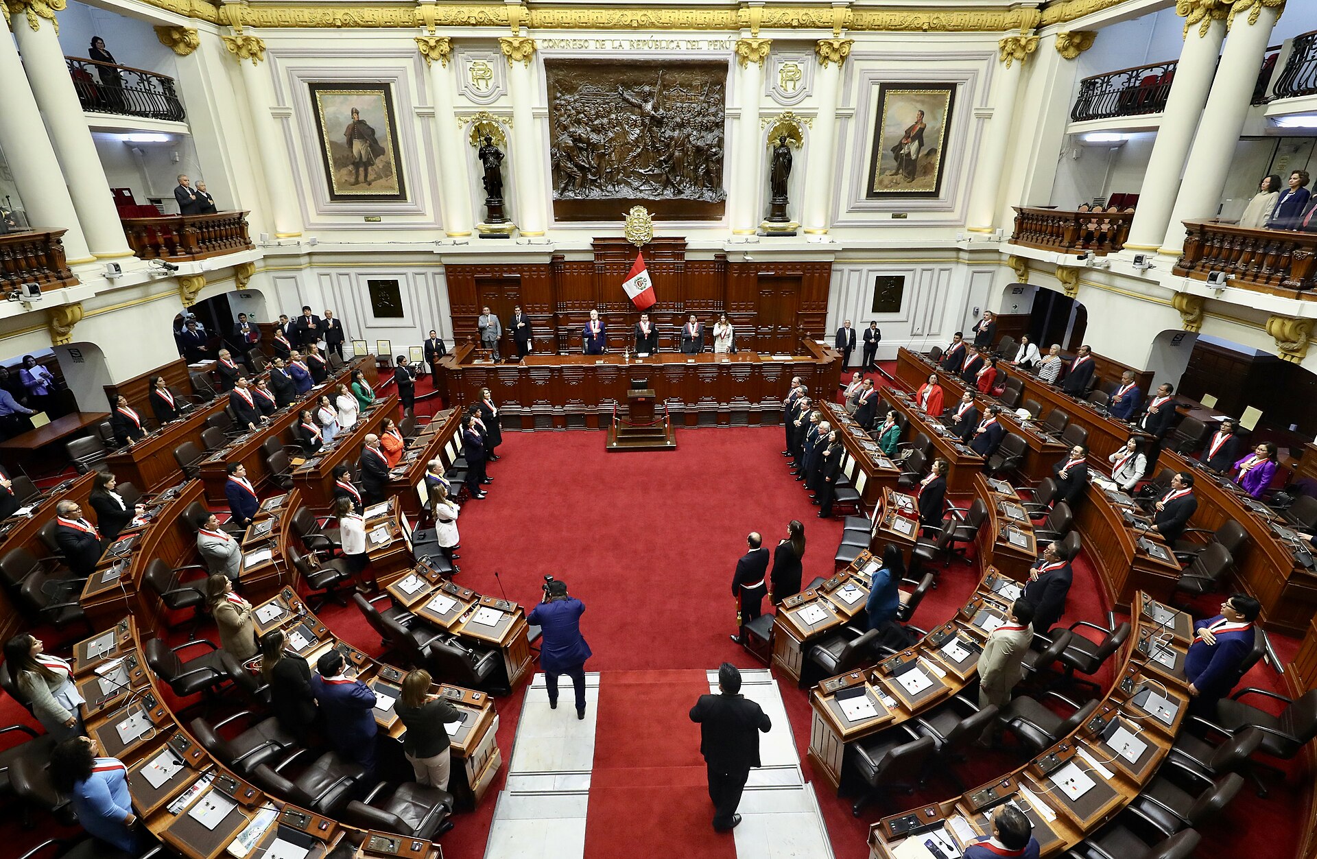 Members of Peru's Congress standing in the red-carpeted session chamber of the Legislative Palace