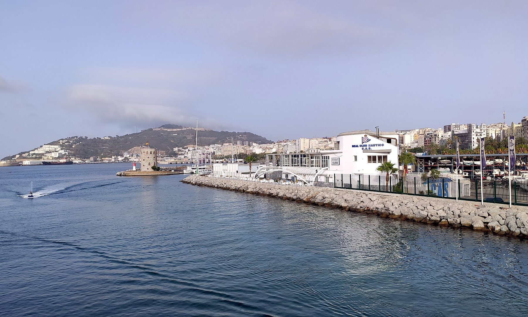 Coastal city with marina, buildings, and hills