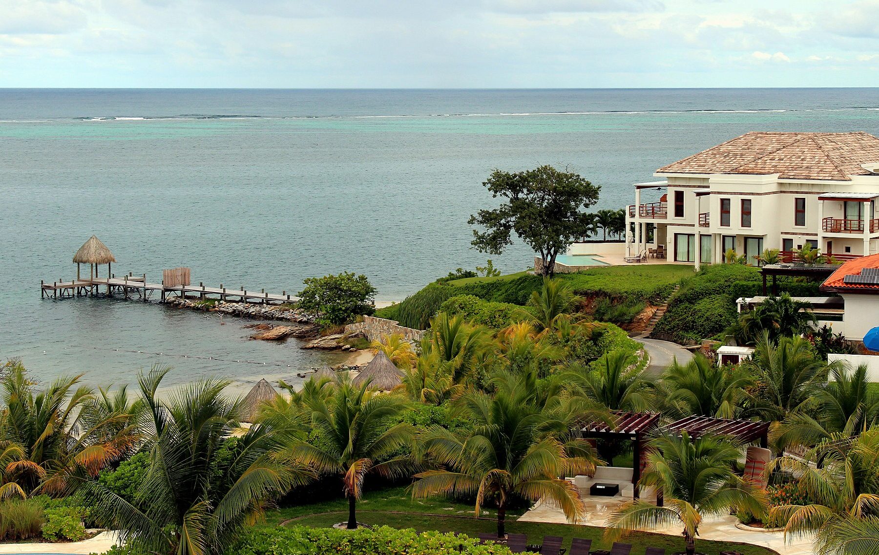 Resort villas with palm gardens and pier on the Caribbean coast at Pristine Bay, Roatán, Honduras