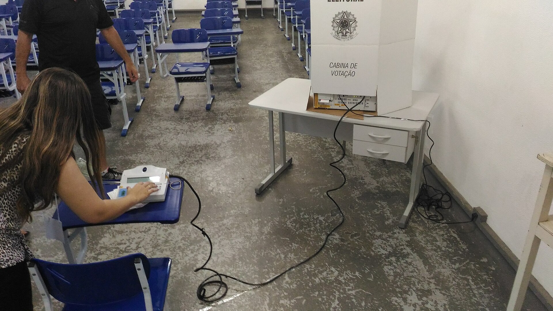 Polling station in Itajubá, Minas Gerais, with a voting booth and an election terminal on a school desk
