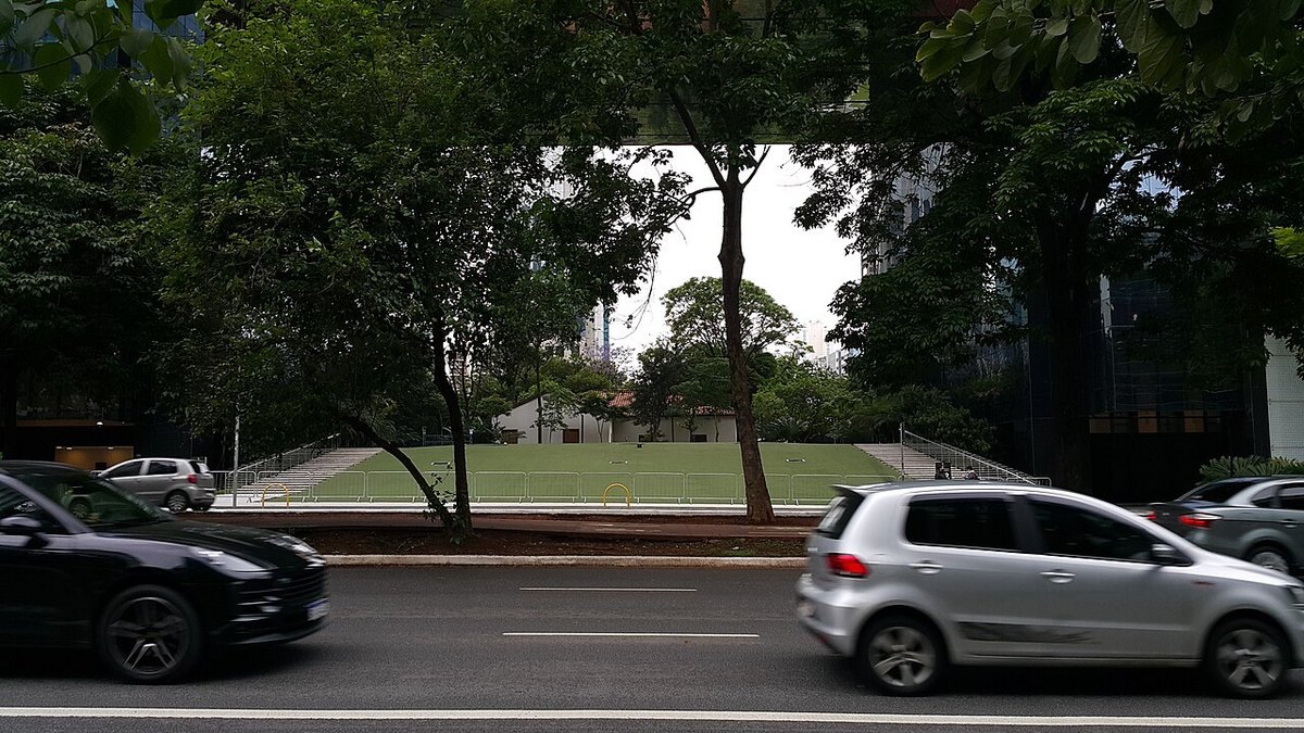 Traffic on Avenida Faria Lima in Sao Paulo, with office towers rising behind the trees