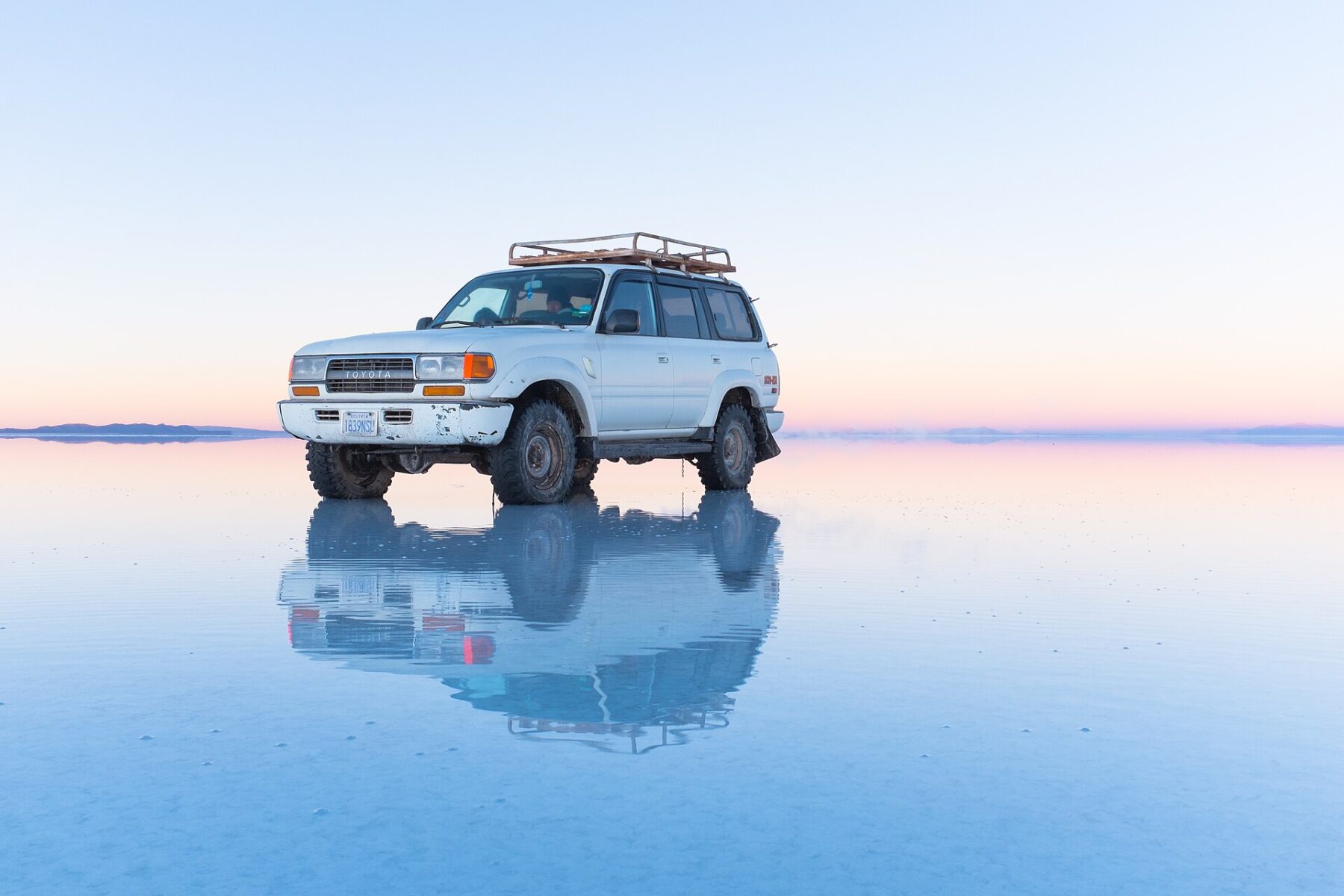 A vehicle crossing the reflective Salar de Uyuni salt flat in Bolivia