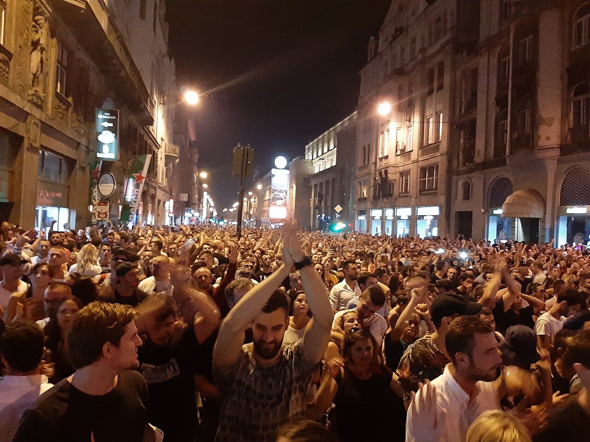 A dense night-time crowd filling a city street at a Solomun open-air show, hands in the air