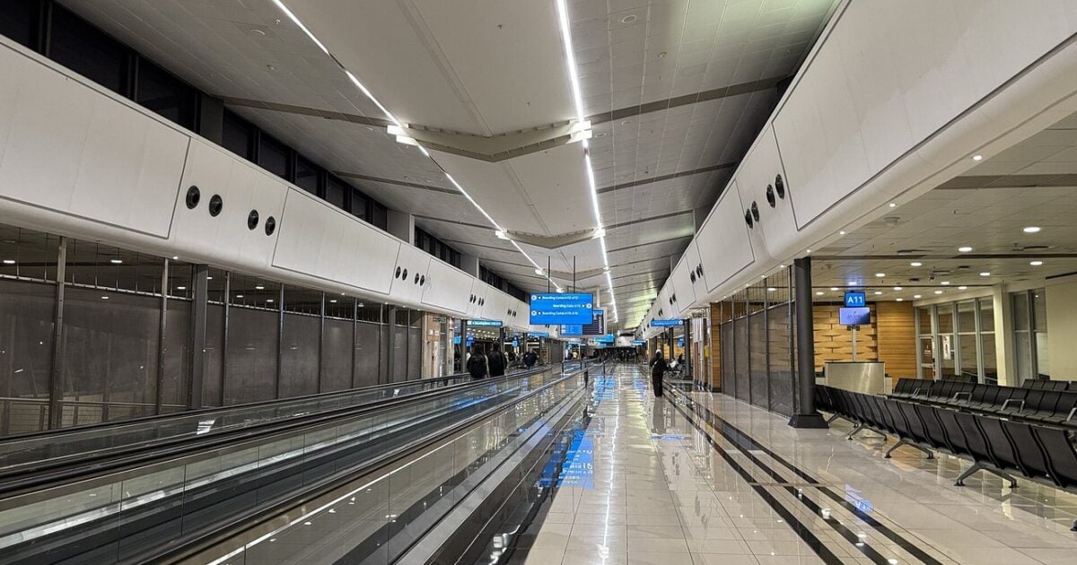An almost empty concourse in Terminal A at OR Tambo International Airport, with moving walkways and gate signs.
