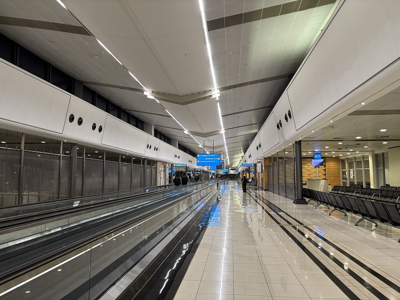 An almost empty concourse in Terminal A at OR Tambo International Airport, with moving walkways and gate signs.