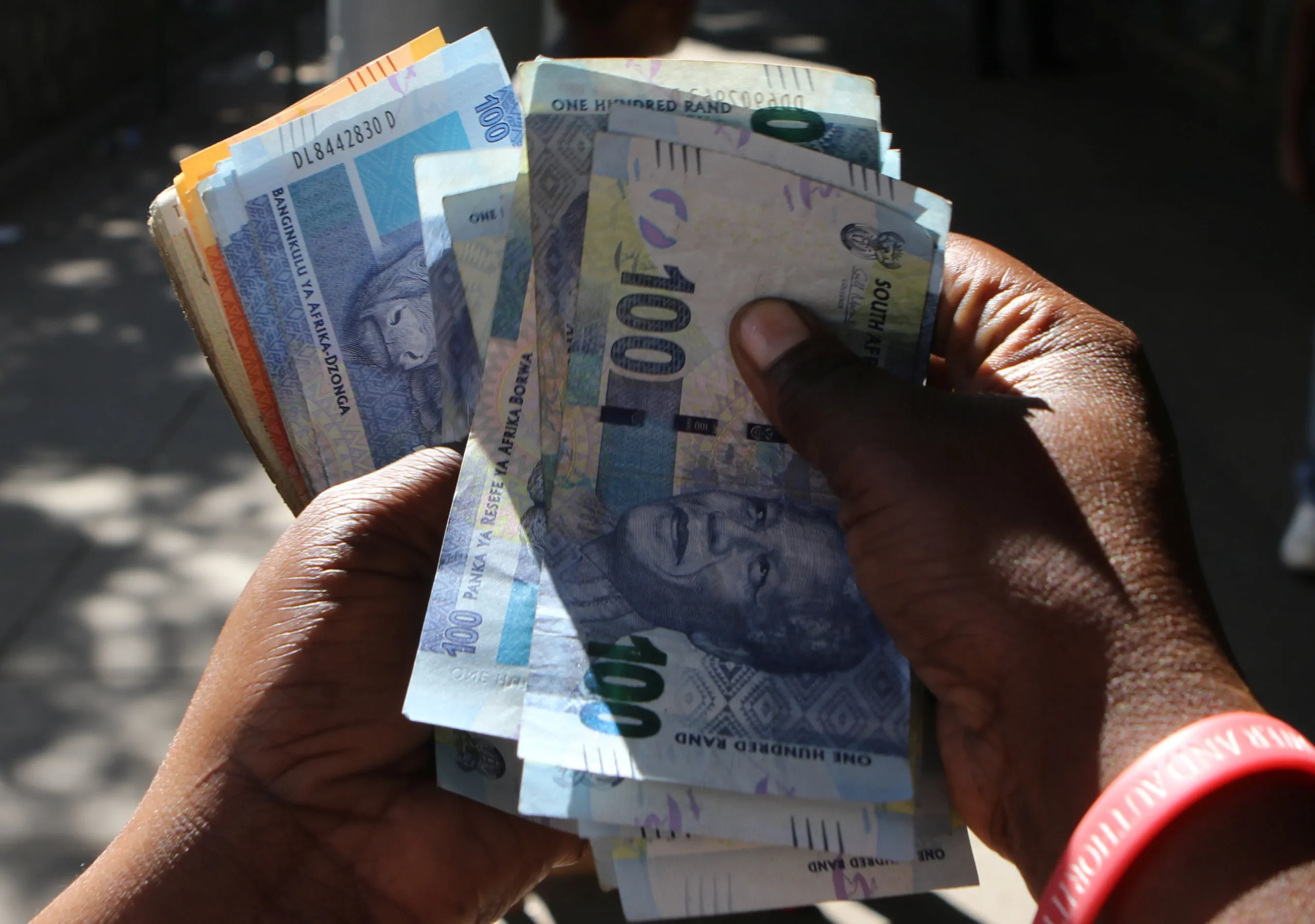 Hands holding South African rand banknotes