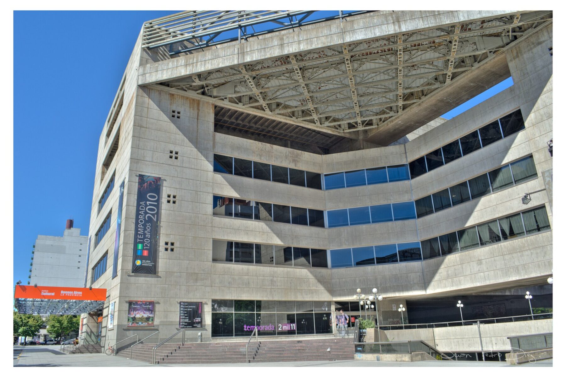 The concrete exterior of the Teatro Argentino in La Plata, with its angled facade, glass bands and steps up to the entrance.