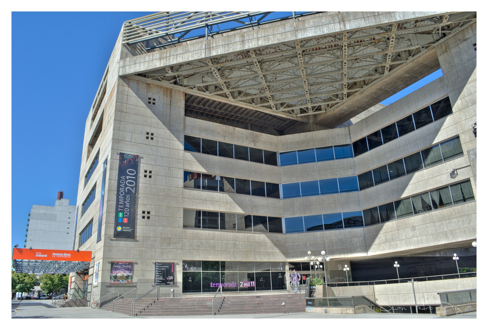 The concrete exterior of the Teatro Argentino in La Plata, with its angled facade, glass bands and steps up to the entrance.
