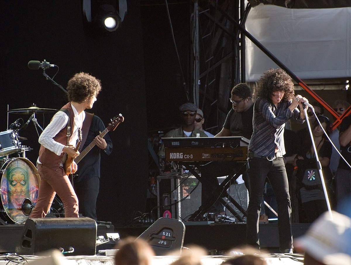 The Mars Volta on stage in daylight, with Omar Rodriguez-Lopez on guitar and Cedric Bixler-Zavala at the microphone