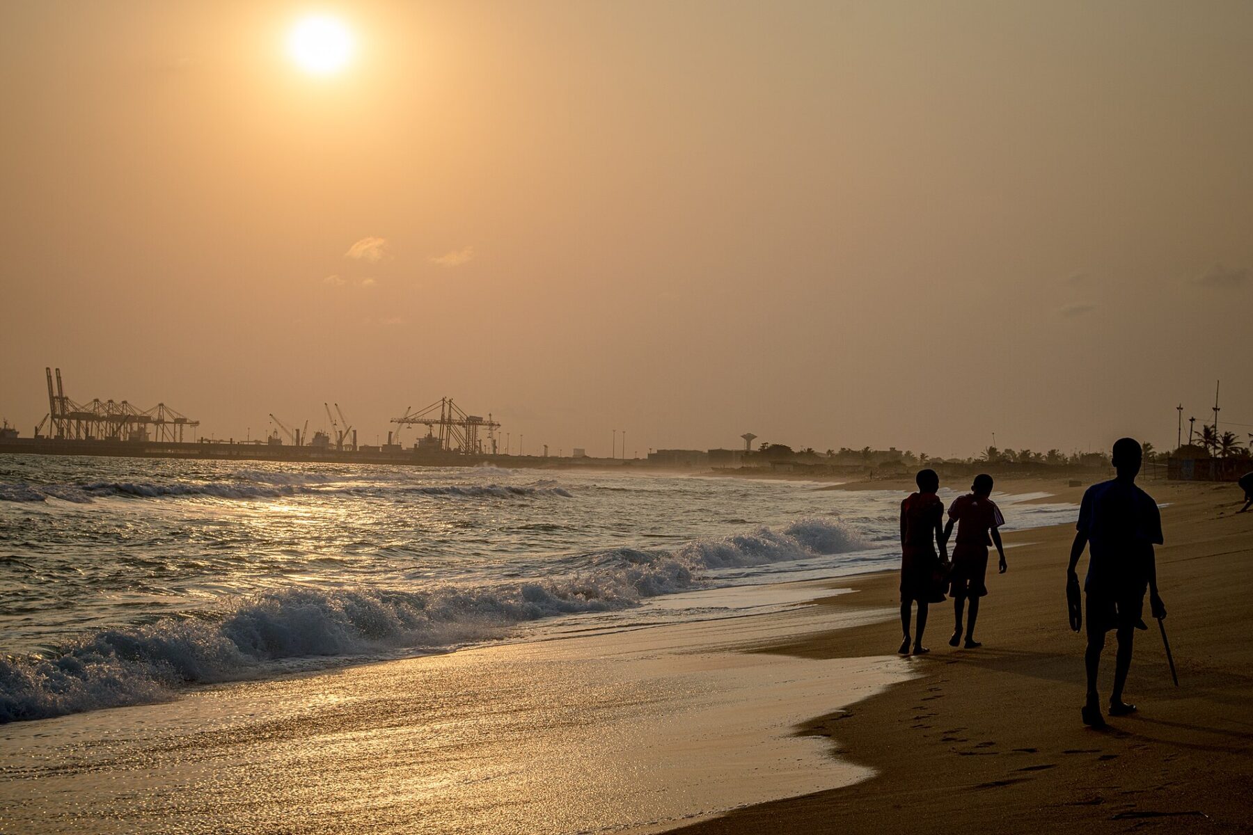 Togo explained 2026 — sunset on Lomé beach with the port cranes on the horizon