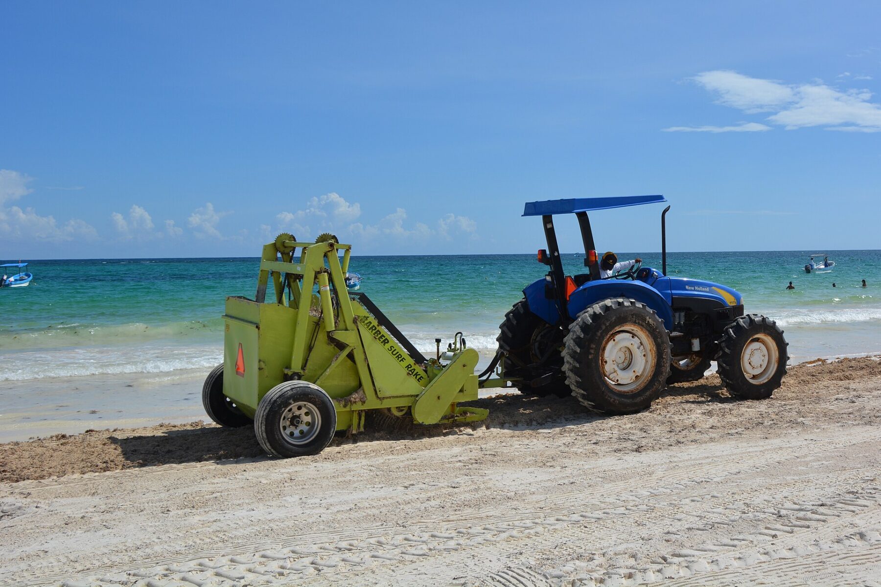 A tractor with a surf rake removes sargassum from the sand on a beach in Tulum, Quintana Roo