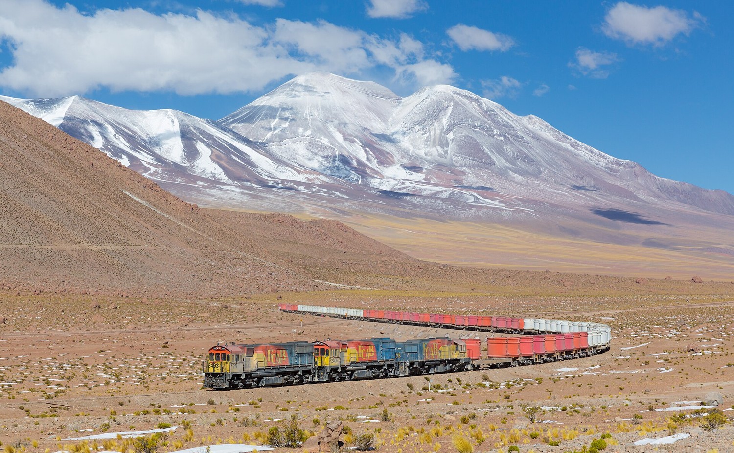 A freight train crossing the Atacama desert in northern Chile with mountains behind