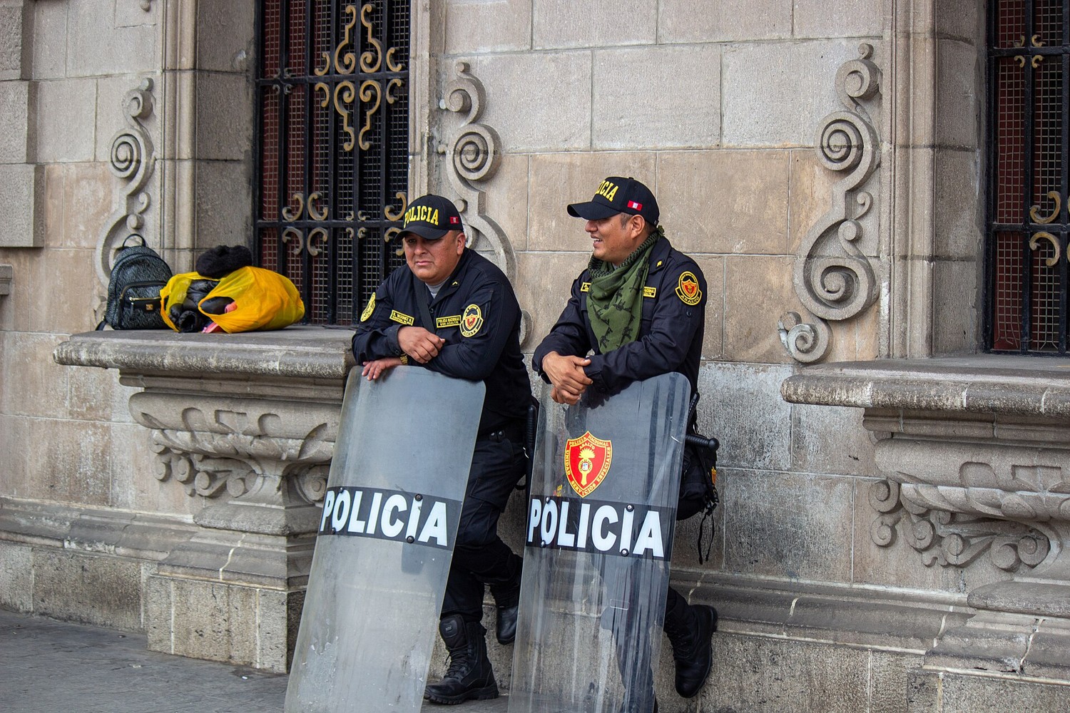 Two Peruvian national police officers with riot shields outside an ornate building