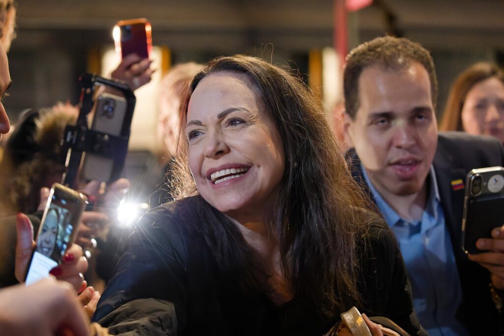 Woman smiling, surrounded by people with phones