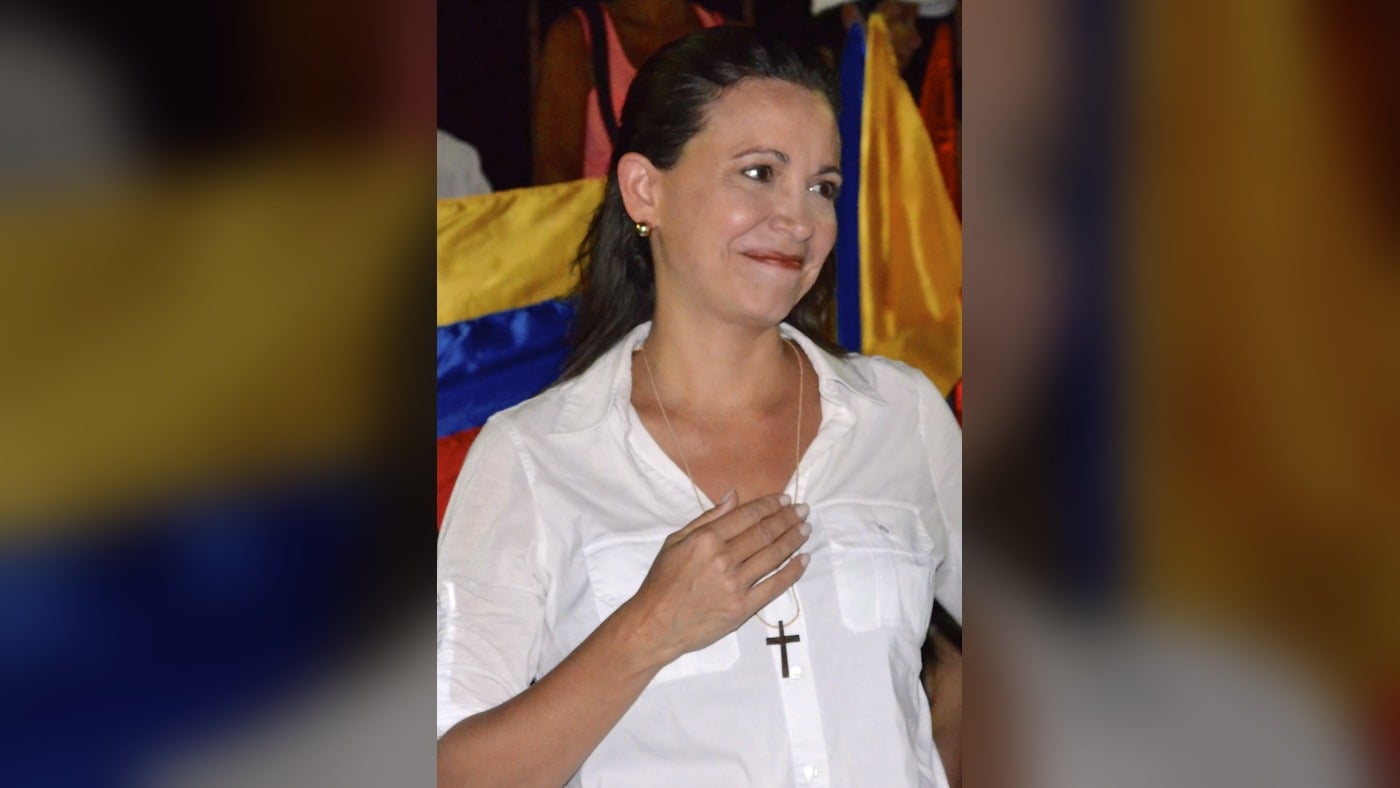 María Corina Machado speaking with a Venezuelan flag behind her