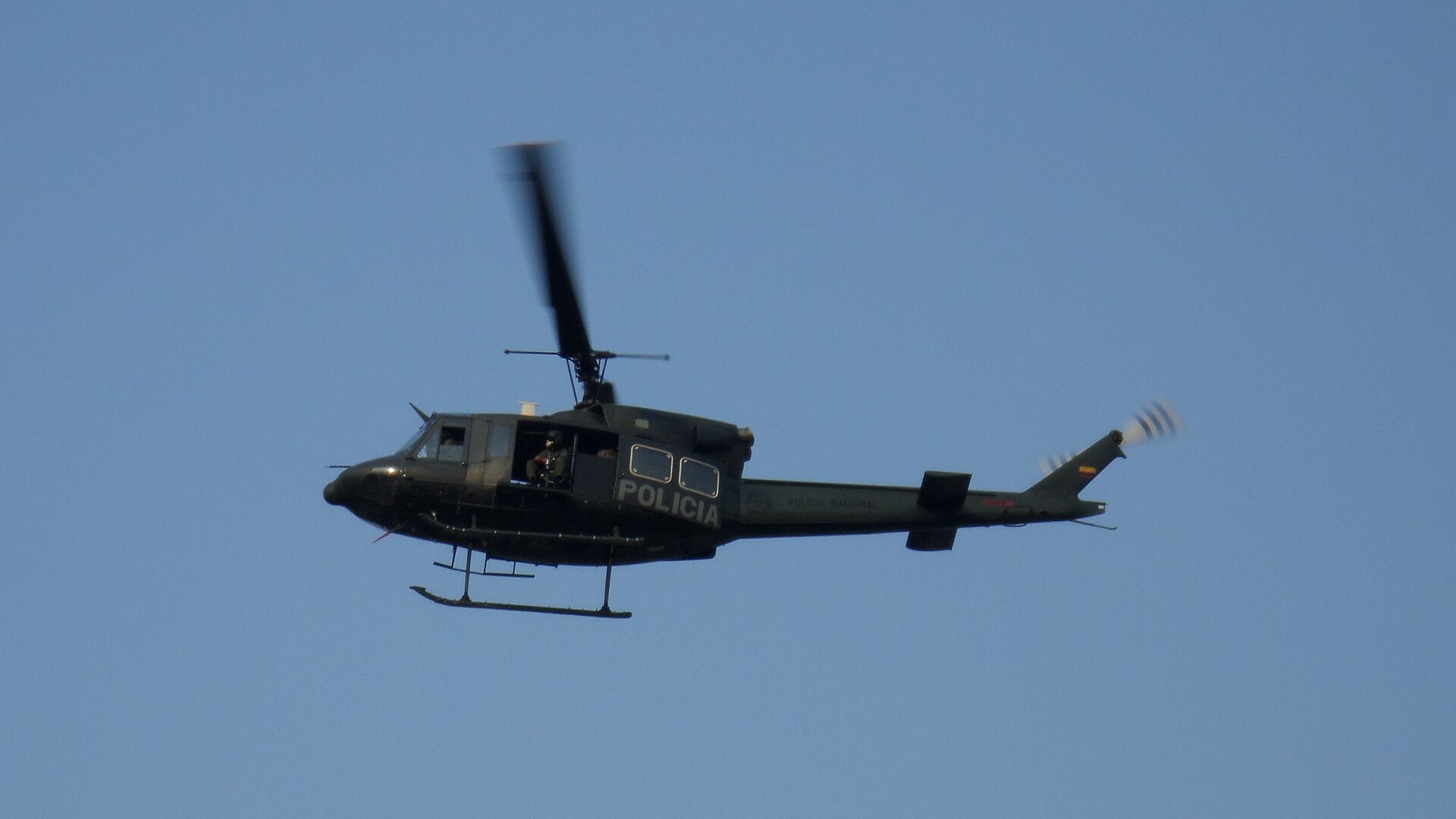 A Colombian National Police helicopter in flight against a blue sky
