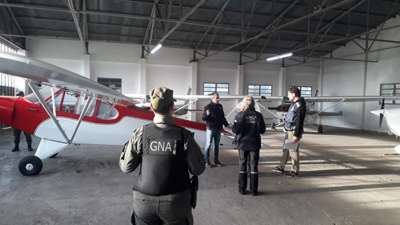 An Argentine Gendarmeria Nacional officer and Customs officials examine light aircraft inside a hangar during Operation ZAFIRO checks in Argentina.