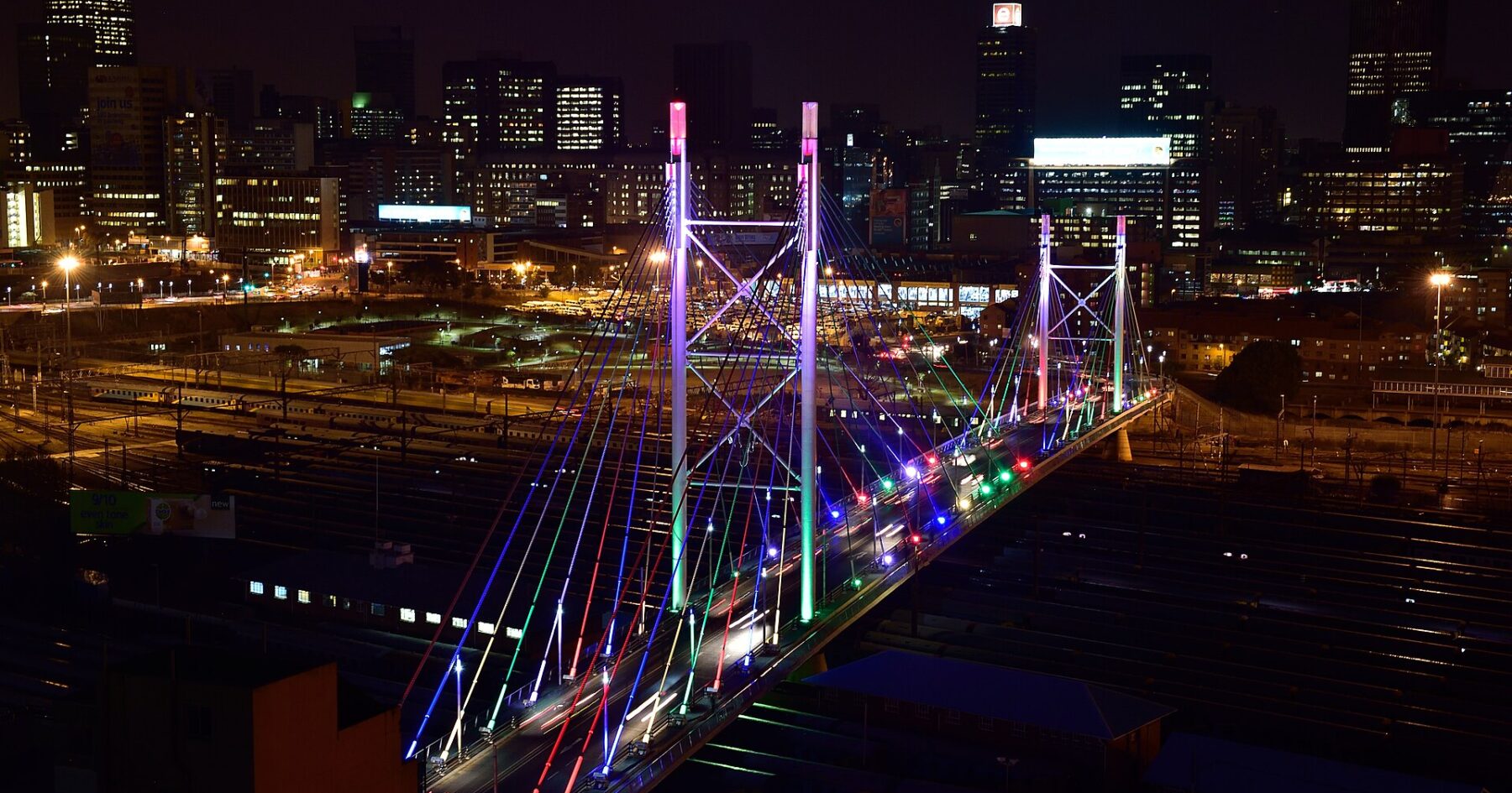 Nelson Mandela Bridge lit up at night with the Johannesburg skyline behind