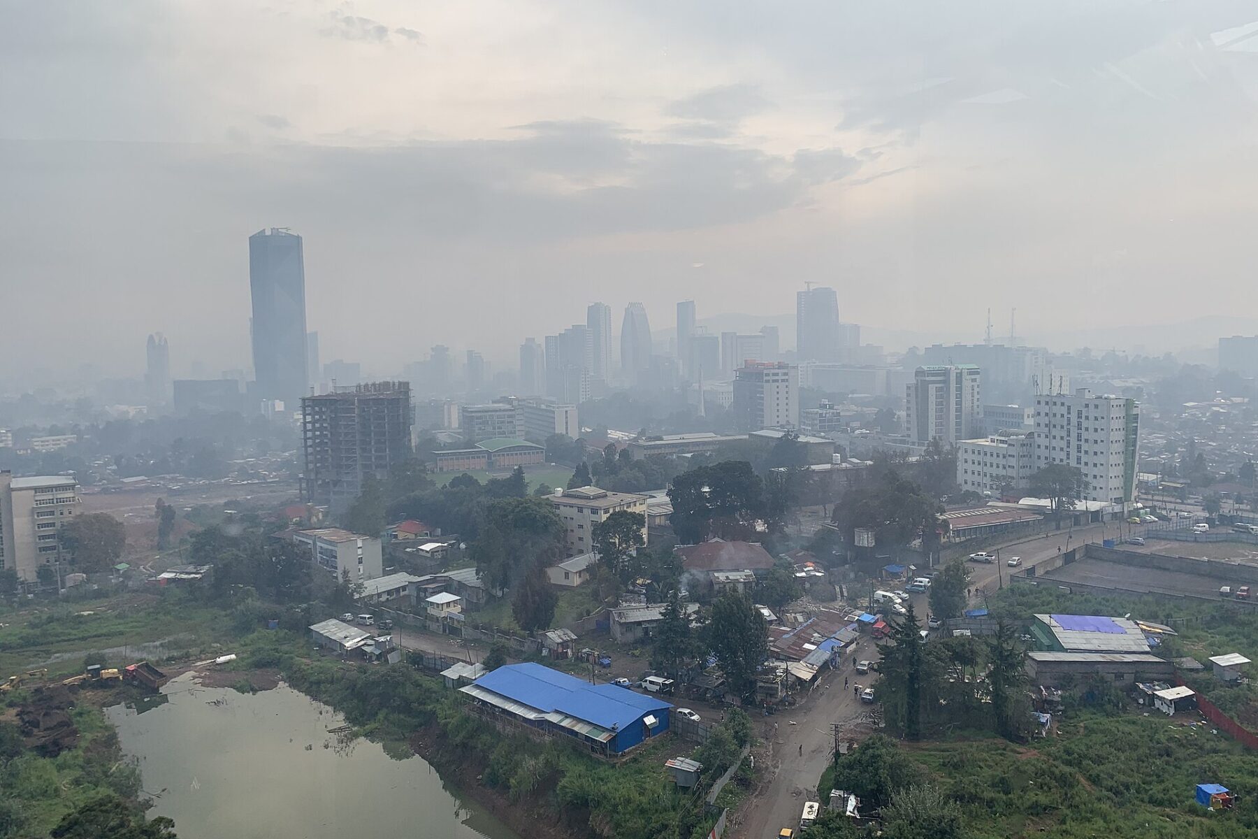 Skyline of Addis Ababa, Ethiopia, seen across a hazy valley with a lake in the foreground