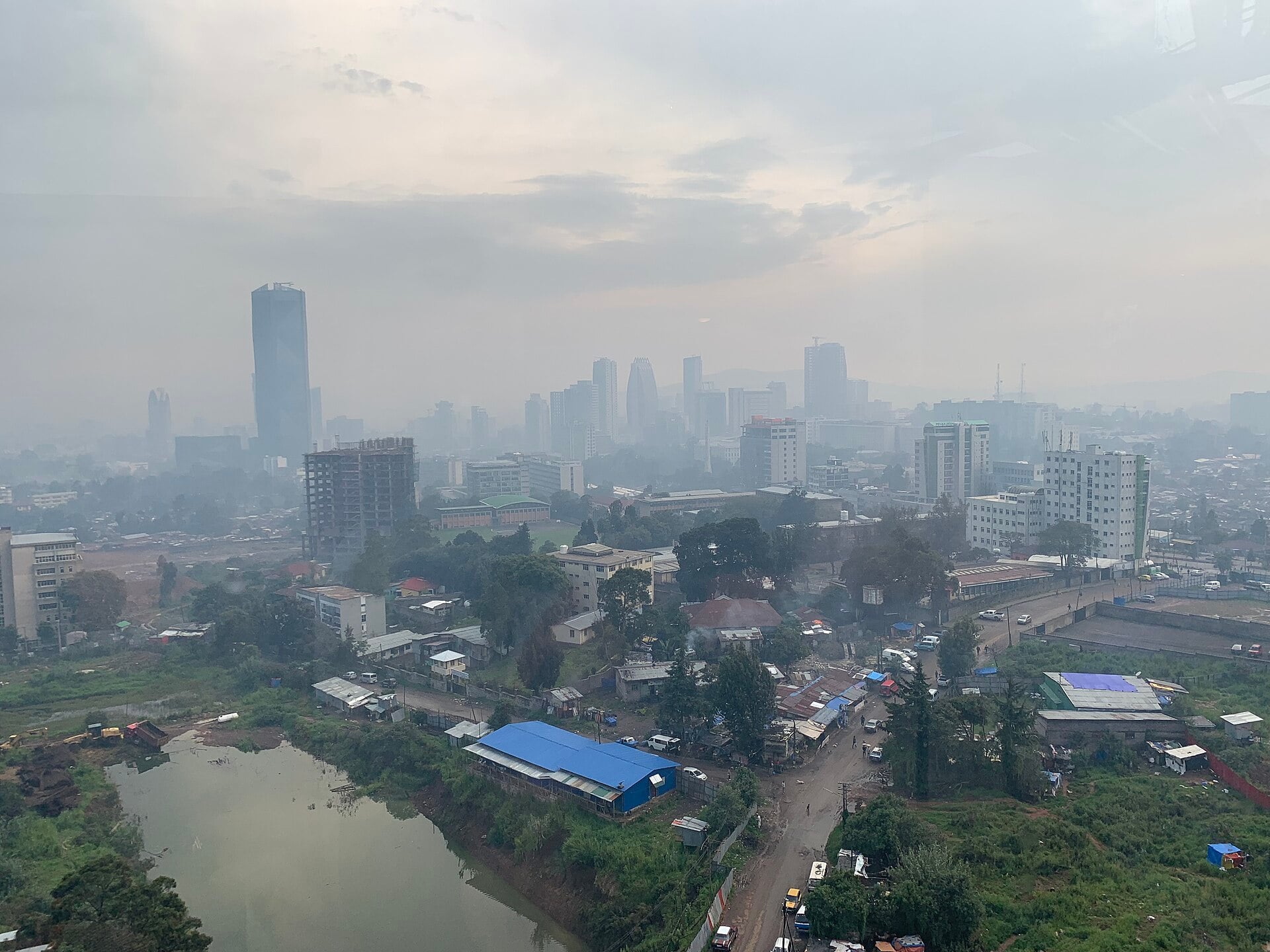 Skyline of Addis Ababa, Ethiopia, seen across a hazy valley with a lake in the foreground
