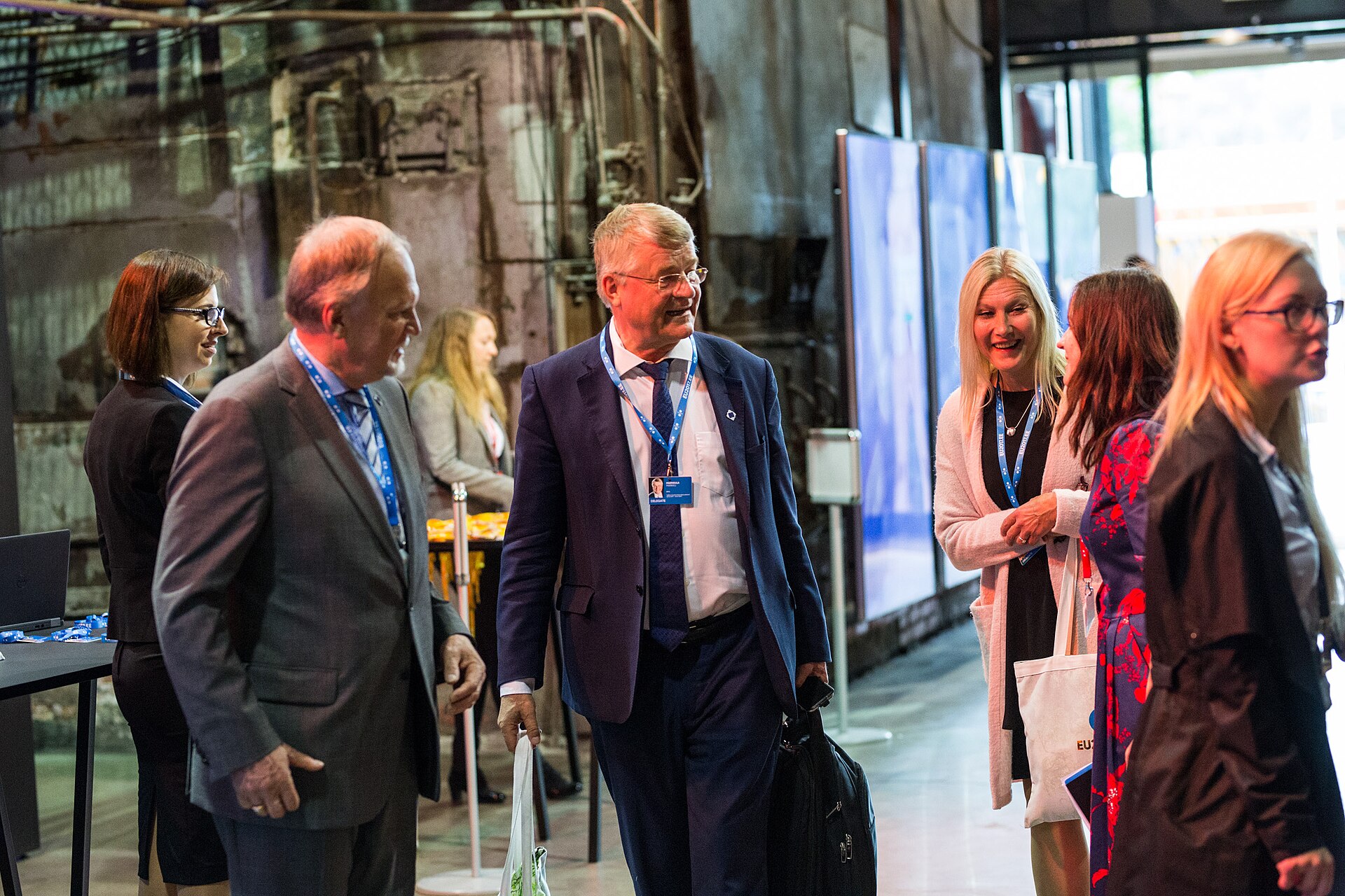 Delegates with name badges talk in an industrial-style conference hall in Tallinn