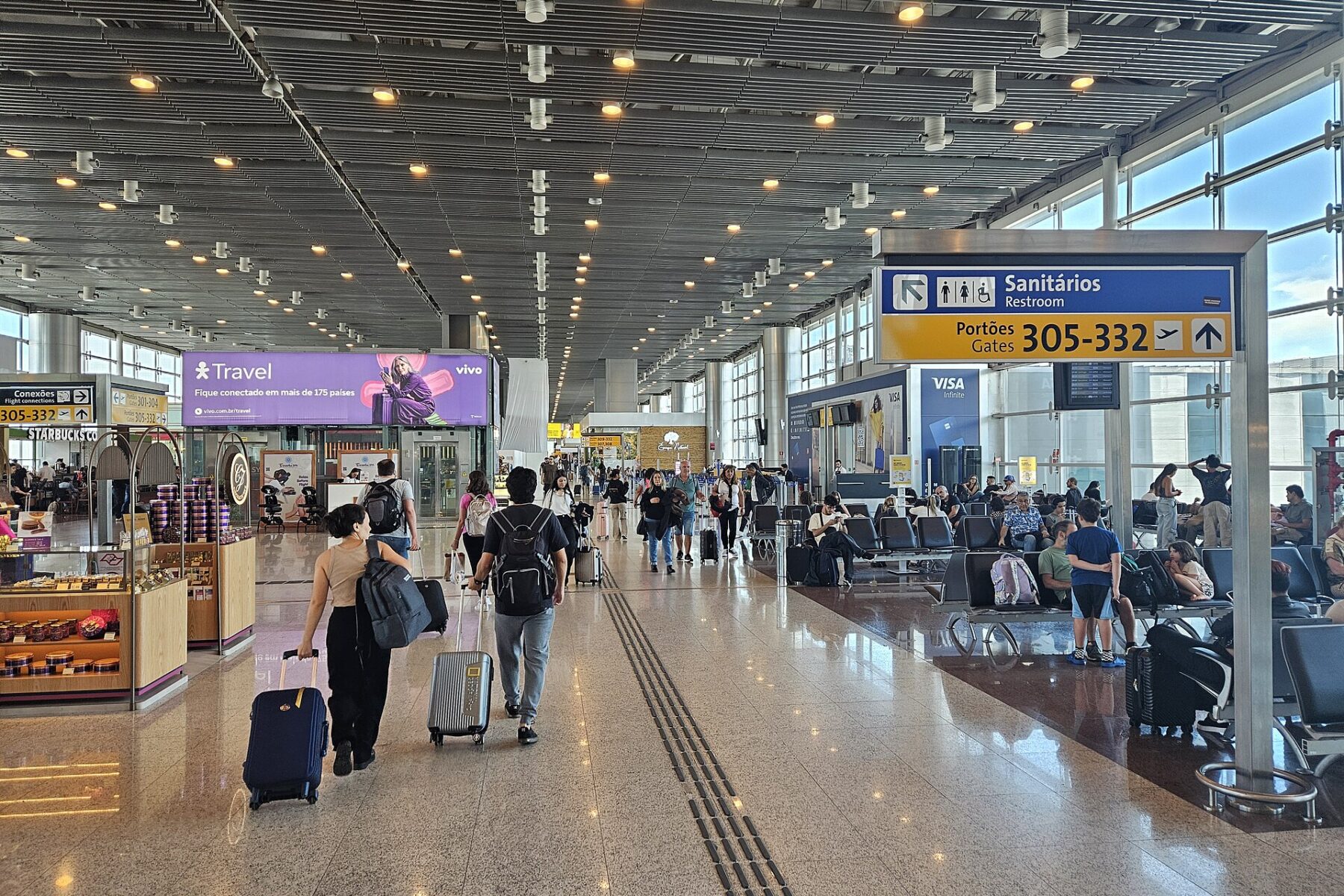 Travellers with luggage walking through the departure lounge of Terminal 3 at São Paulo Guarulhos airport