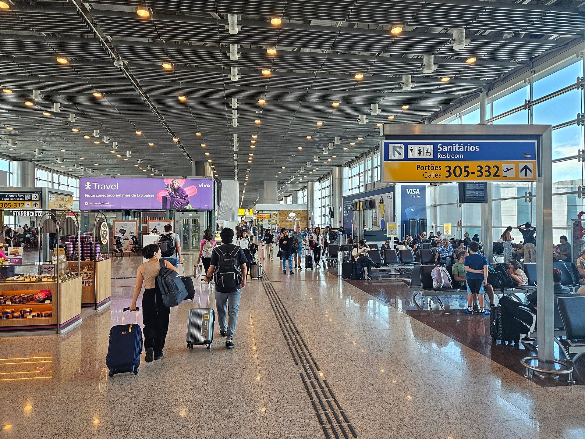 Travellers with luggage walking through the departure lounge of Terminal 3 at São Paulo Guarulhos airport